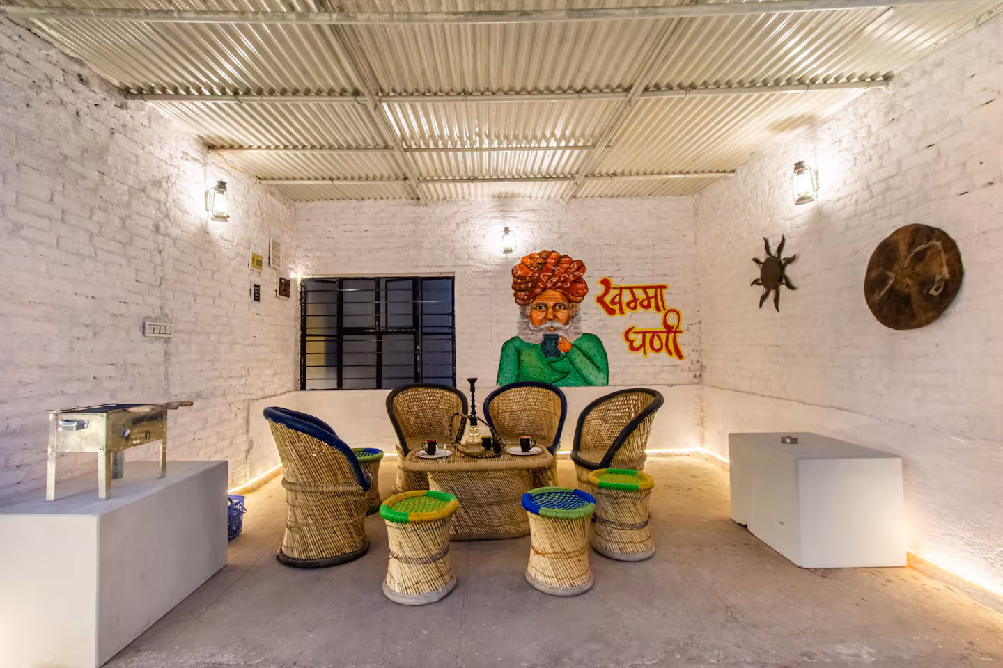 Covered terrace lounge with cane seating, low table and Rajasthani wall art at Polaris Art Terrace, Jaipur
