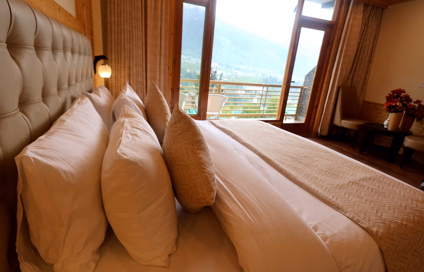 Bed with layered linen beside open balcony doors and mountain views at Polaris Golden Wood, Manali