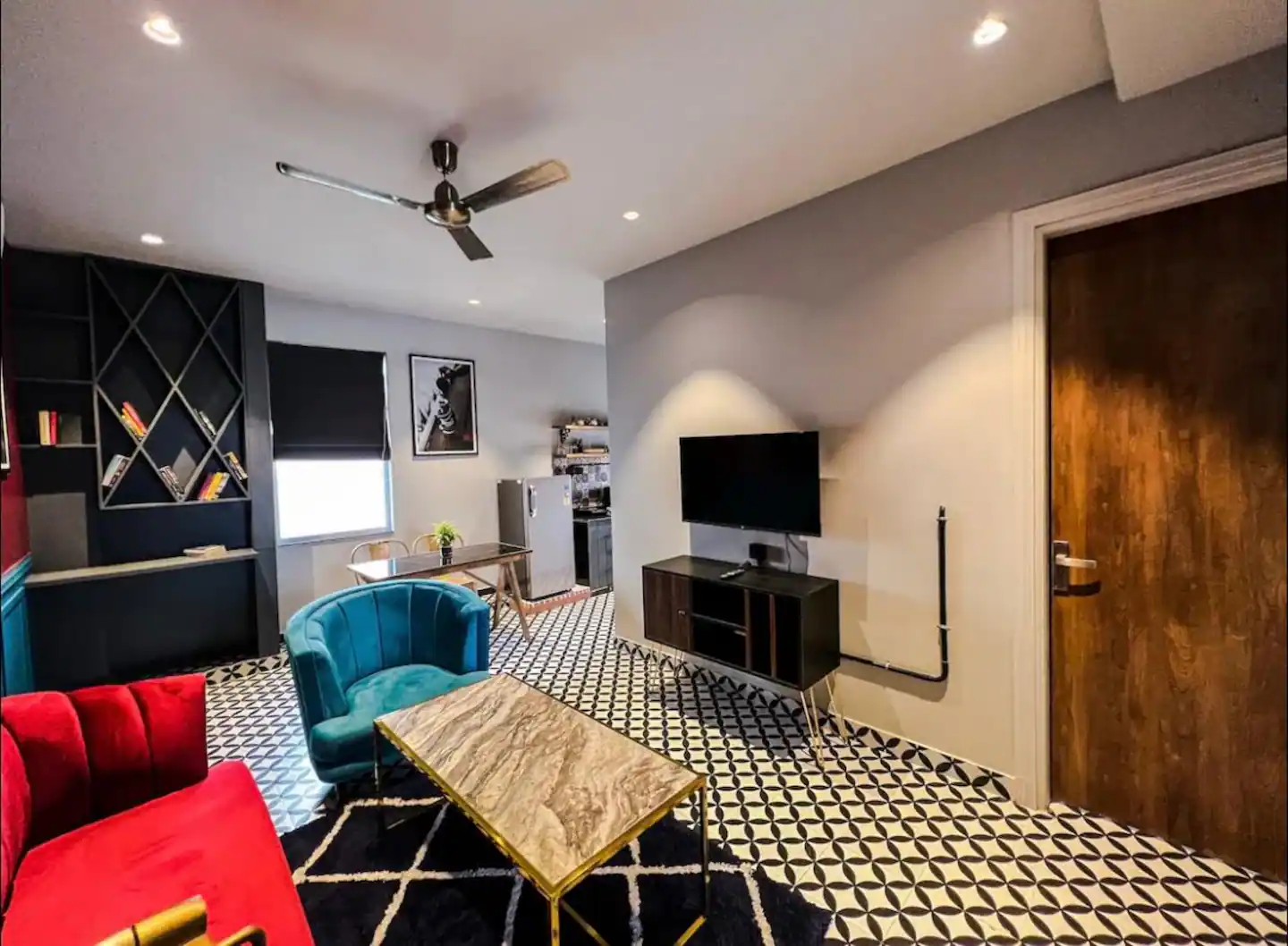 Living room with red velvet sofa, teal armchair and patterned tile flooring at Polaris Royal Terrace, Jaipur