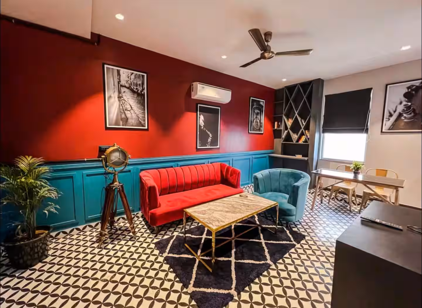 Lounge with deep red wall, framed art and gold coffee table at Polaris Royal Terrace, Jaipur