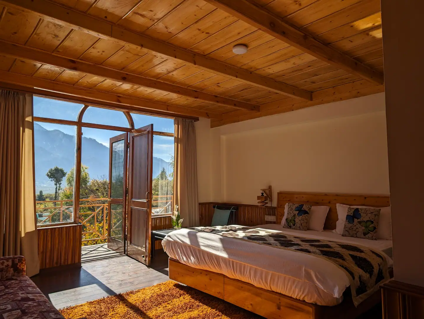 Wood-panelled bedroom at Polaris Himalayan Chalet, Simsa, Manali, with balcony doors open to mountain views