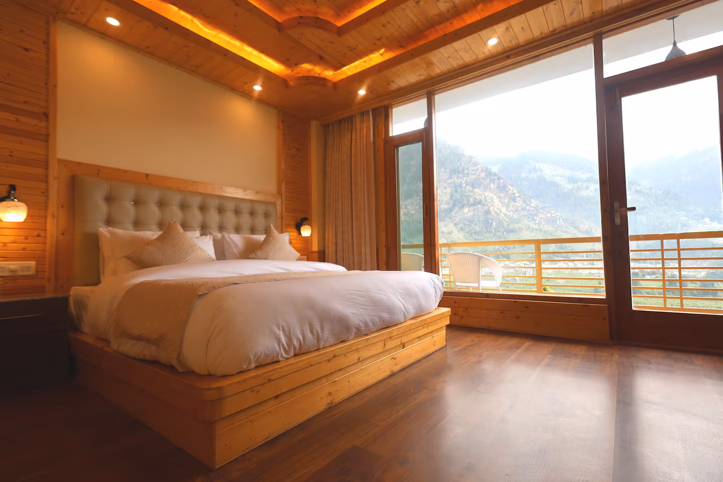 Wood-panelled bedroom at Polaris Golden Wood, Chhiyal, Manali, opening onto a balcony with Himalayan valley views