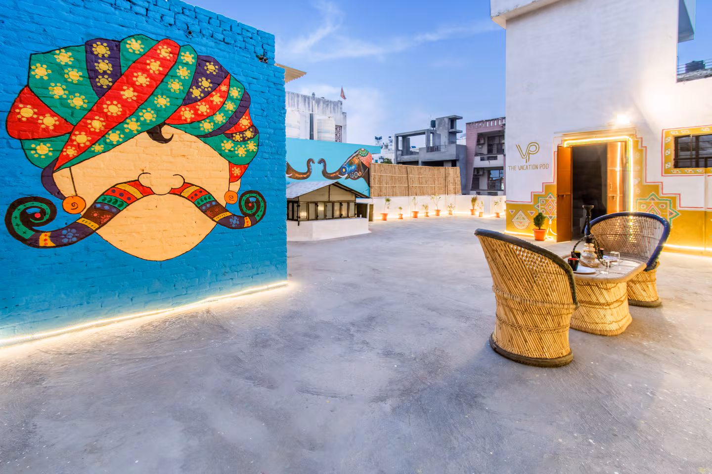 Terrace corner with turbaned Rajasthani mural, cane armchair and warm lighting at Polaris Art Terrace, Jaipur
