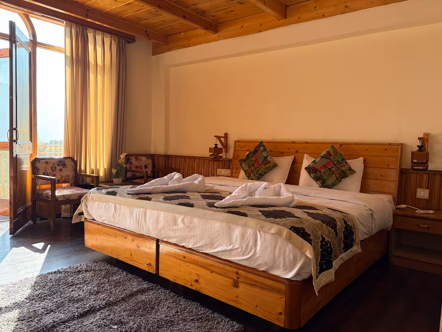 Wooden bedroom with pine ceiling and seating at Polaris Himalayan Chalet, Manali