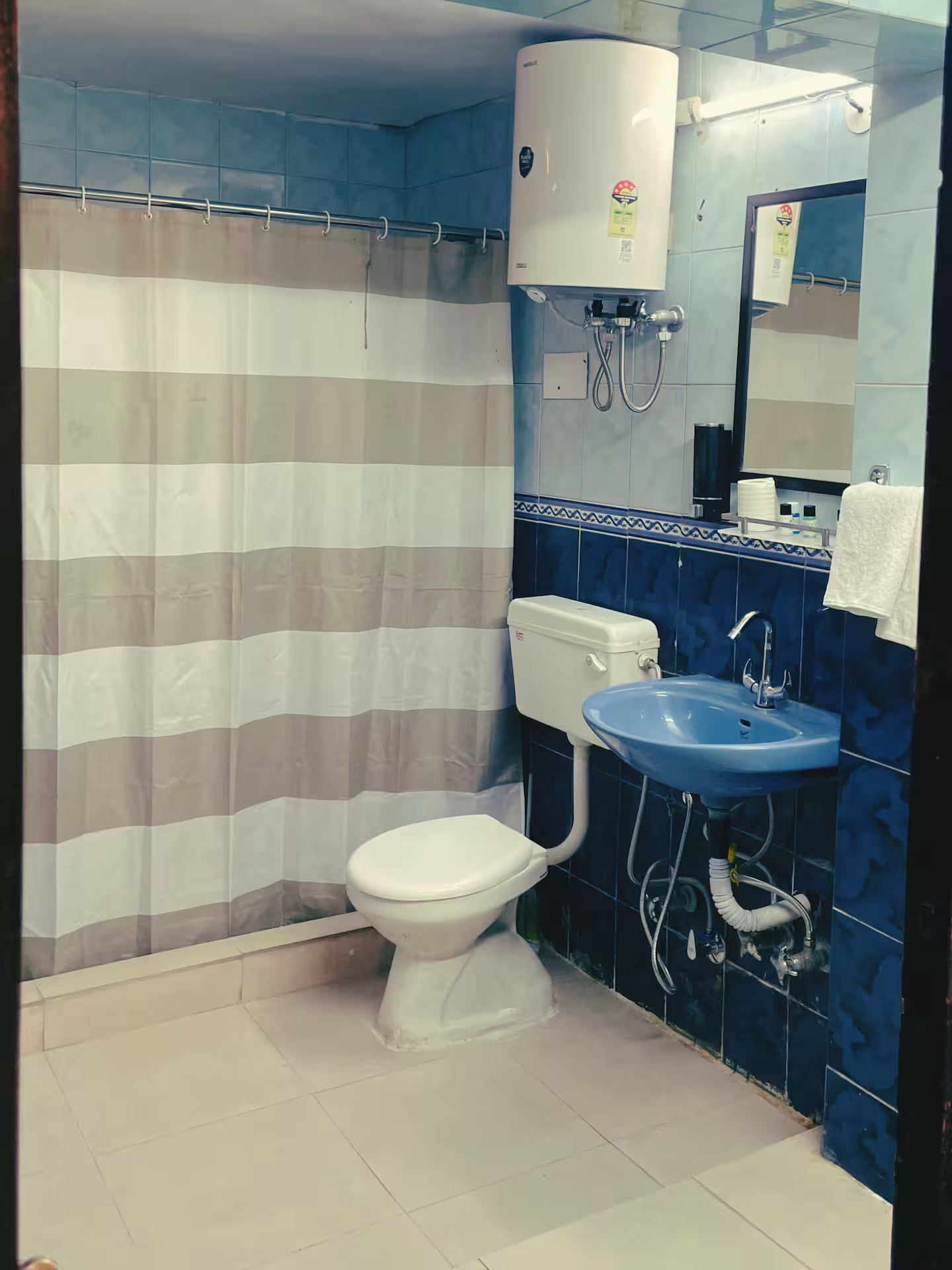 Bathroom with hot water geyser, basin and mirror at Polaris Alpine, Mussoorie