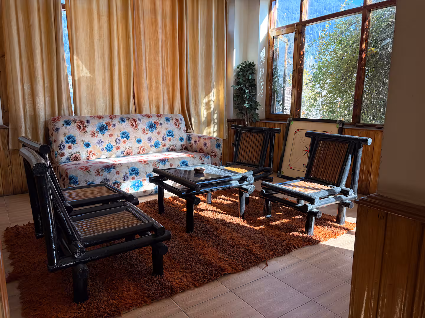 Glazed sitting area with cane chairs at Polaris Himalayan Chalet, Manali