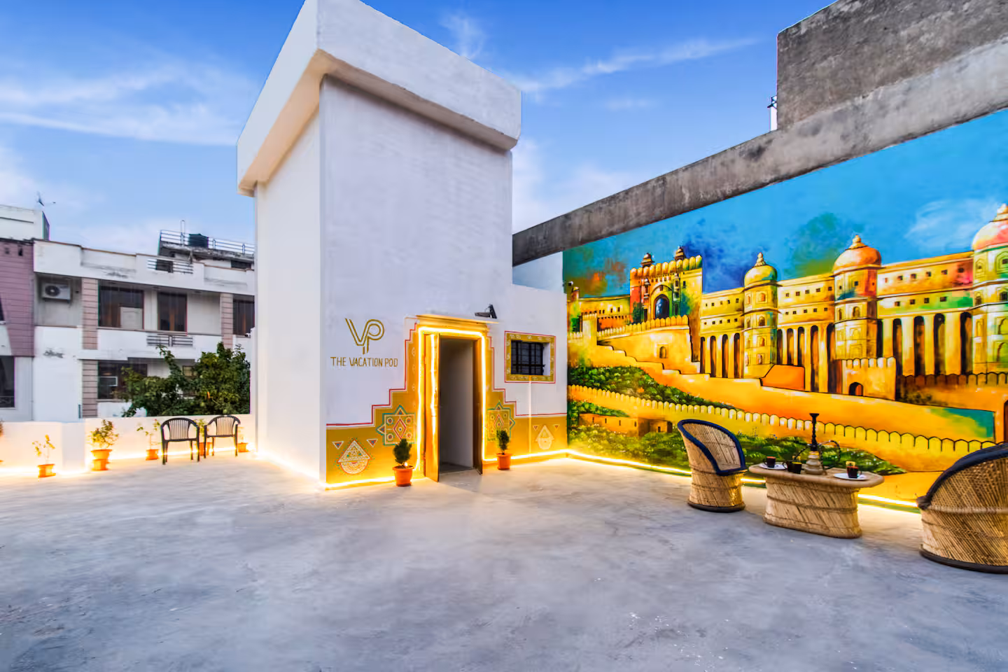 Private terrace at twilight with a Rajasthan-inspired mural of Hawa Mahal and cane seating at Polaris Art Terrace, Shyam Nagar, Jaipur