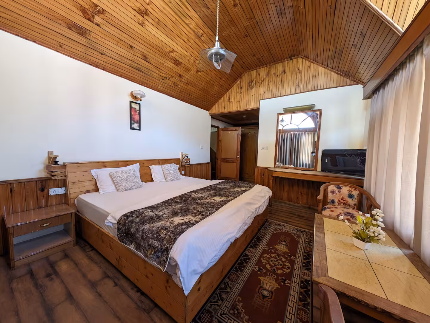 Wood-lined bedroom with dressing mirror at Polaris Himalayan Chalet, Manali