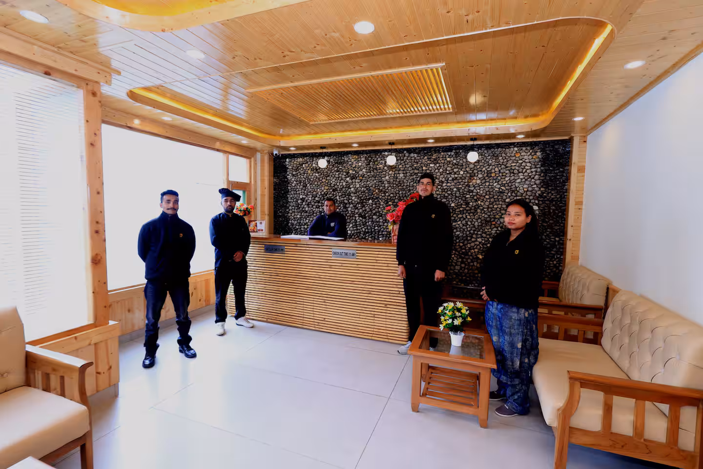 Reception and shared lounge with pine ceiling and pebble wall at Polaris Golden Wood, Manali