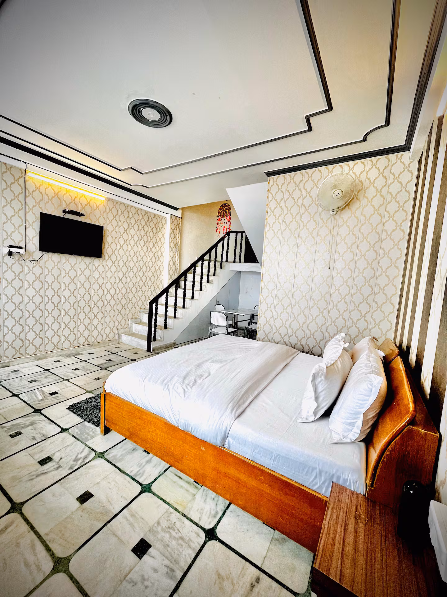 Bedroom with wooden bed, TV and staircase to the upper floor at Polaris Alpine, Mussoorie