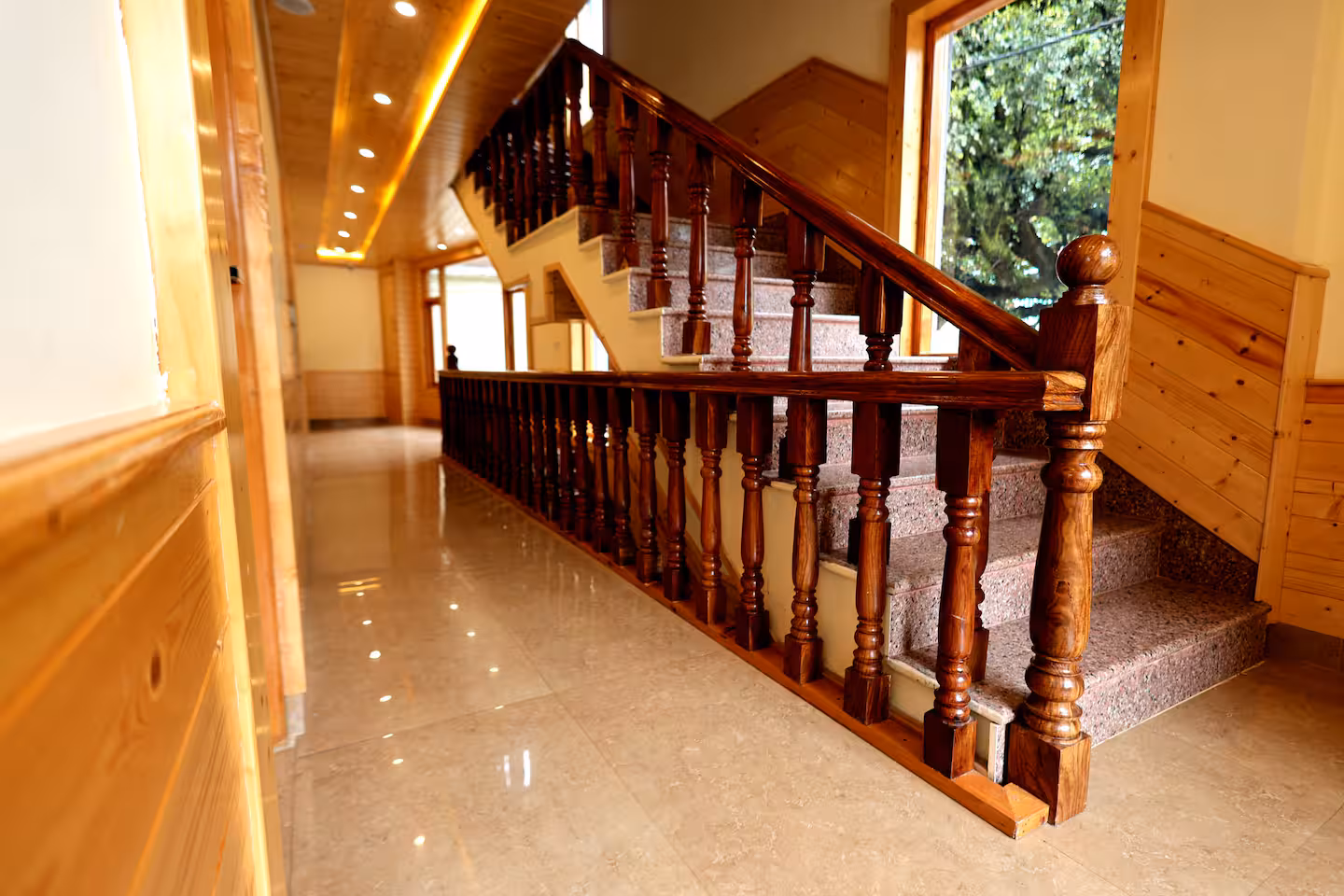 Wood-lined hallway and polished timber stairway inside Polaris Golden Wood, Manali