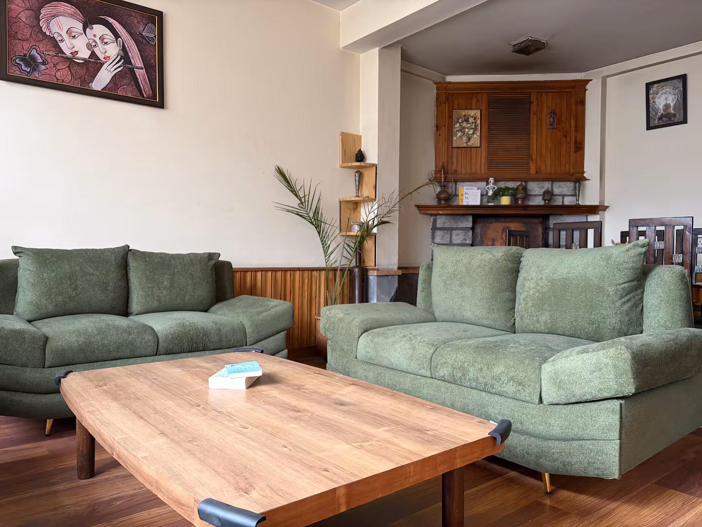 Living room with green sofas and fireplace at Polaris Himalayan Chalet, Manali