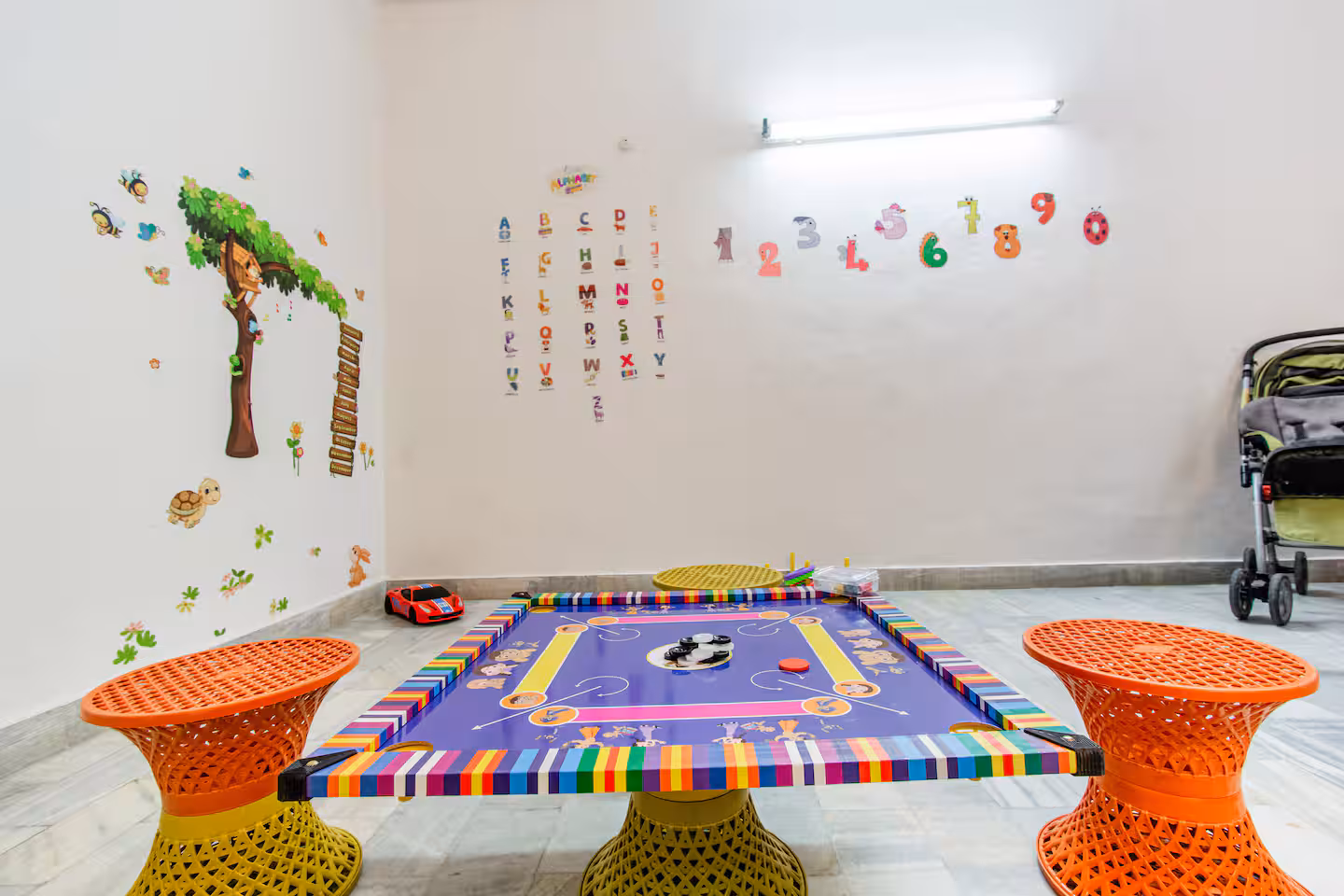 Kids' play room with colourful floor mat, stools and playful wall decals at Polaris Art Terrace, Jaipur