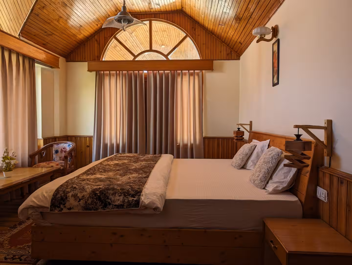 Bedroom with vaulted timber ceiling and arched window at Polaris Himalayan Chalet, Manali